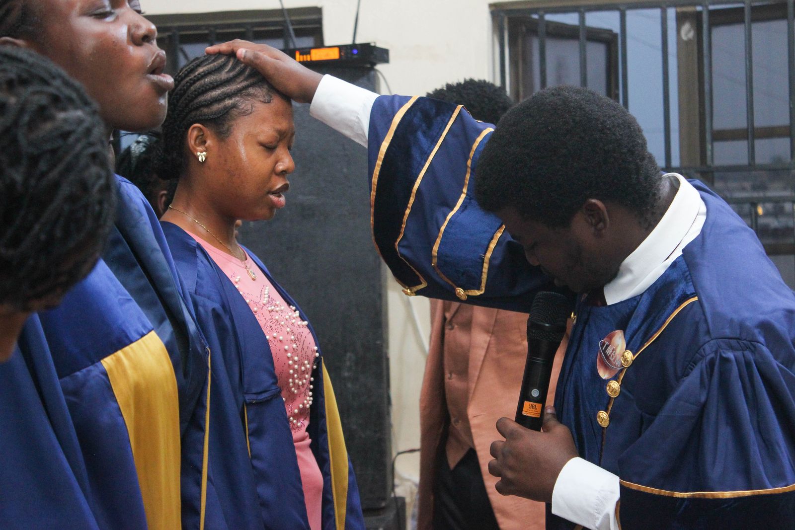 A minister in a gown laying hands on an attendee in prayer