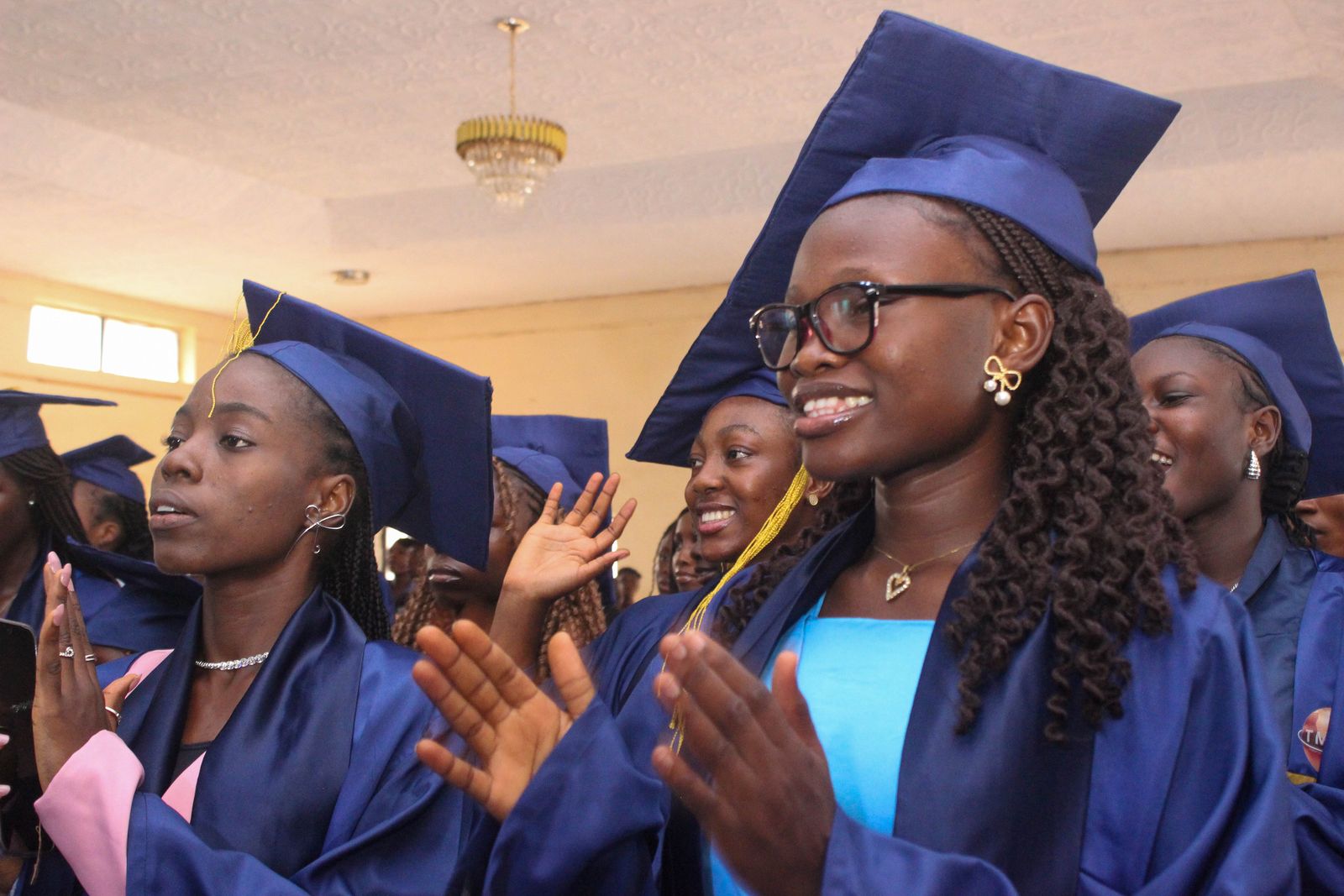 Graduates in blue gowns and caps applauding