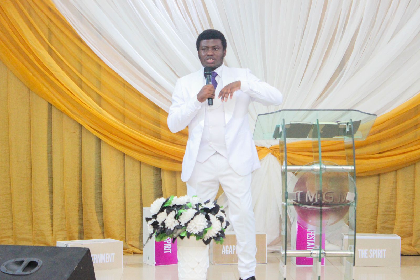 Our pastor in a white suit preaching from the pulpit