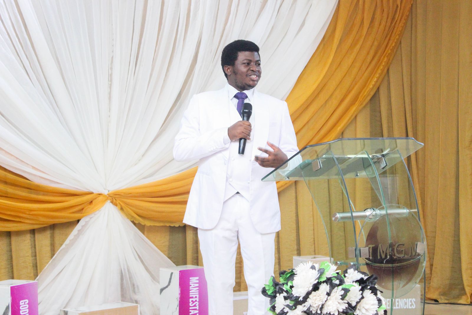Our pastor in white ministering with a microphone