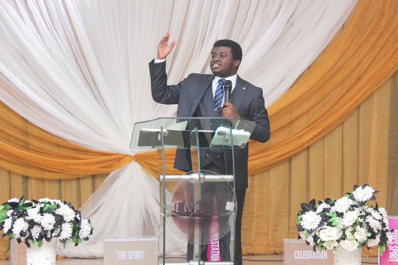 A minister raising his hand in prayer at the pulpit