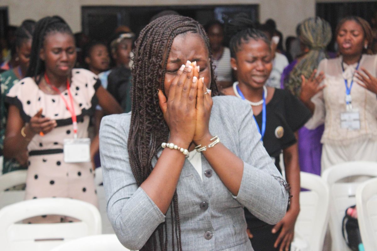 A young woman praying with her hands over her face
